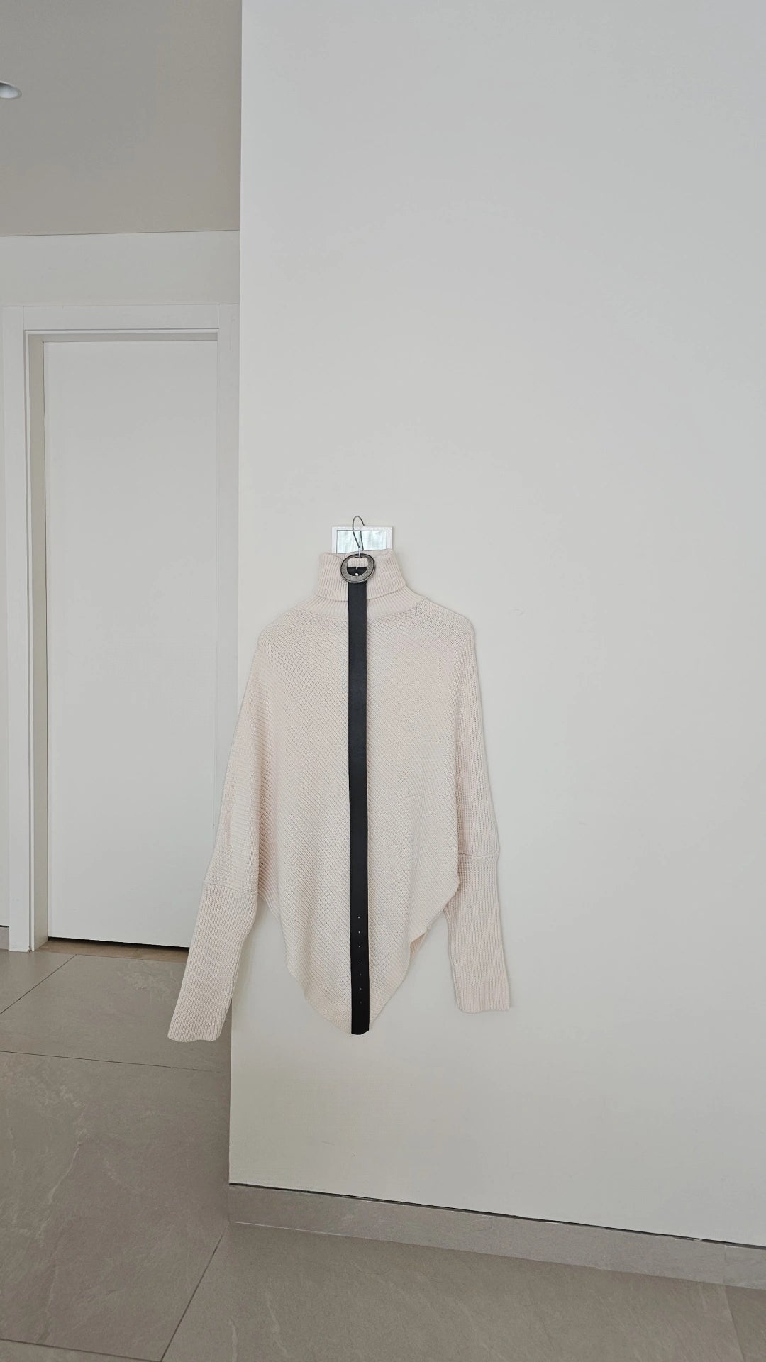 Off-white asymmetric ribbed turtleneck sweater with a black faux leather belt