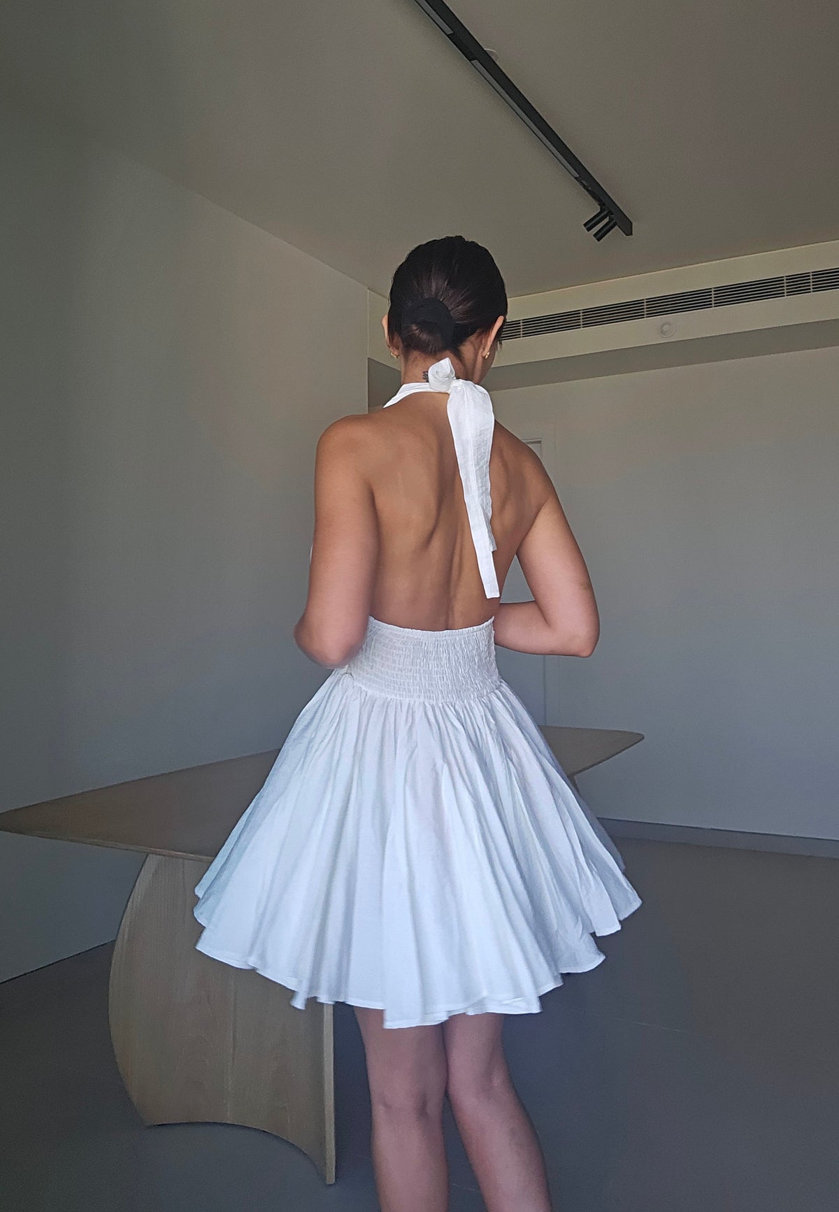 White plunging halter mini dress with a ruched waist and gold buttons